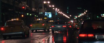 Movie still from “Last Action Hero” (1993), directed by John McTiernan – Cars are driving down a wet street at night; Extreme Wide shot, Low angle