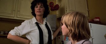 Movie still from “Last Action Hero” (1993), directed by John McTiernan – A woman is looking in the mirror while a child looks on; Medium shot, Over the shoulder angle