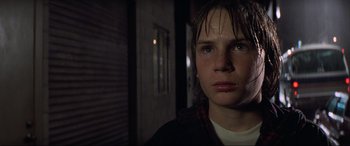 Movie still from “Last Action Hero” (1993), directed by John McTiernan – A young man with wet hair stares into the camera; Close Up shot, Low angle