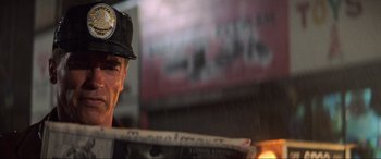 Movie still from “Last Action Hero” (1993), directed by John McTiernan – A man wearing a black hat and holding a newspaper; Close Up shot, Low angle
