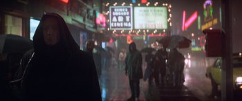 Movie still from “Last Action Hero” (1993), directed by John McTiernan – A group of people walking down a street at night; Medium shot, Over the shoulder angle