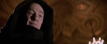 Movie still from “Last Action Hero” (1993), directed by John McTiernan – An older man wearing a black hooded robe; Close Up shot, Low angle