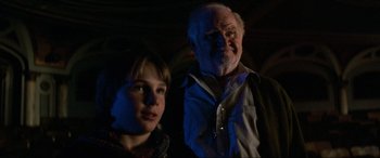 Movie still from “Last Action Hero” (1993), directed by John McTiernan – An older man and a young girl standing next to each other; Close Up shot, Over the shoulder angle