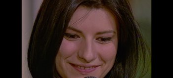 Movie still from “Laura Pausini: Pleasure to Meet You” (2022), directed by Ivan Cotroneo – A person with a microphone smiling; Extreme Close Up shot, High angle