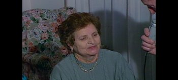 Movie still from “Laura Pausini: Pleasure to Meet You” (2022), directed by Ivan Cotroneo – An older woman sitting in a chair looking at the camera; Close Up shot, High angle