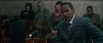 Movie still from “Law Abiding Citizen” (2009), directed by F. Gary Gray – A man in a suit and tie at a podium; Close Up shot, Over the shoulder angle