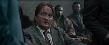 Movie still from “Law Abiding Citizen” (2009), directed by F. Gary Gray – A man wearing a suit and tie sitting in front of other men; Close Up shot, Over the shoulder angle