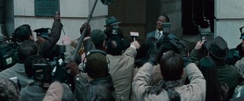 Movie still from “Law Abiding Citizen” (2009), directed by F. Gary Gray – A crowd of people gathered around a man in a suit; Medium shot, Over the shoulder angle
