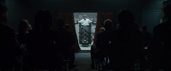 Movie still from “Law Abiding Citizen” (2009), directed by F. Gary Gray – A man standing in front of a group of people in a room; Wide shot, Over the shoulder angle