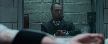 Movie still from “Law Abiding Citizen” (2009), directed by F. Gary Gray – A man in a suit sitting in front of a brick wall; Close Up shot, Over the shoulder angle