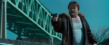 Movie still from “Law Abiding Citizen” (2009), directed by F. Gary Gray – A man holding a gun while standing in front of a bridge; Medium shot, Low angle