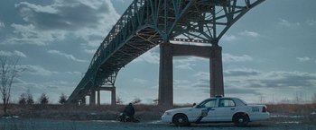 Movie still from “Law Abiding Citizen” (2009), directed by F. Gary Gray – A white police car parked under a large bridge; Extreme Wide shot, Low angle