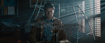 Movie still from “Law Abiding Citizen” (2009), directed by F. Gary Gray – A man sitting in front of a table with a bird cage; Medium shot, Low angle
