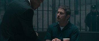 Movie still from “Law Abiding Citizen” (2009), directed by F. Gary Gray – Two men are talking to each other at a table; Medium shot, Over the shoulder angle