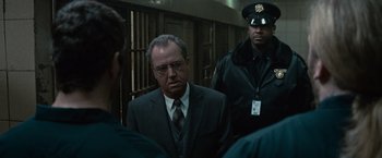 Movie still from “Law Abiding Citizen” (2009), directed by F. Gary Gray – A man wearing a suit and tie standing next to two other men; Medium shot, Over the shoulder angle