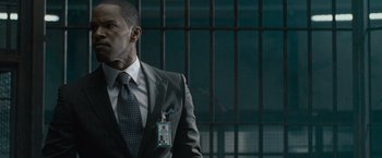 Movie still from “Law Abiding Citizen” (2009), directed by F. Gary Gray – A man in a suit and tie standing in front of bars; Close Up shot, Over the shoulder angle