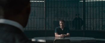 Movie still from “Law Abiding Citizen” (2009), directed by F. Gary Gray – A man sitting at a table in front of a jail cell; Wide shot, Low angle