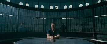 Movie still from “Law Abiding Citizen” (2009), directed by F. Gary Gray – A man sitting at a table in front of a jail cell; Wide shot, Low angle