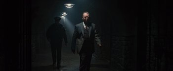 Movie still from “Law Abiding Citizen” (2009), directed by F. Gary Gray – A man in a suit walking down a dark hallway; Wide shot, Low angle