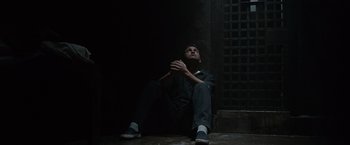 Movie still from “Law Abiding Citizen” (2009), directed by F. Gary Gray – A man sitting on the ground in a dark room; Wide shot, High angle