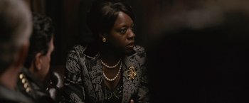 Movie still from “Law Abiding Citizen” (2009), directed by F. Gary Gray – A woman in a black and white jacket with a gold cross on her chest; Close Up shot, Over the shoulder angle