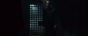 Movie still from “Law Abiding Citizen” (2009), directed by F. Gary Gray – A man standing in front of a door in a dark room; Medium shot, Low angle