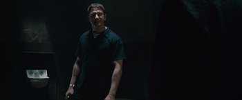 Movie still from “Law Abiding Citizen” (2009), directed by F. Gary Gray – A man standing in a dark room with his hands in his pockets; Medium shot, Over the shoulder angle