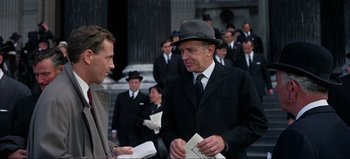 Movie still from “Lawrence of Arabia” (1962), directed by David Lean – A man in a suit and a hat talking to another man in a suit and a hat; Medium shot, Over the shoulder angle