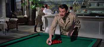 Movie still from “Lawrence of Arabia” (1962), directed by David Lean – A man in a military uniform playing a game of billiards; Medium shot, Over the shoulder angle