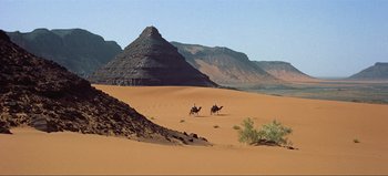 Movie still from “Lawrence of Arabia” (1962), directed by David Lean – A group of people riding on the back of a camel; Extreme Wide shot, High angle