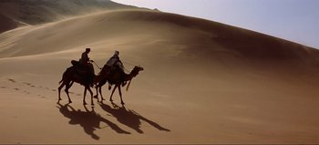 Movie still from “Lawrence of Arabia” (1962), directed by David Lean – Two men riding on the backs of camels in the desert; Extreme Wide shot, Low angle