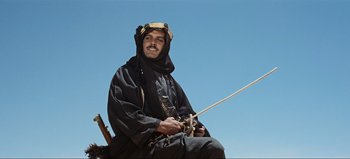 Movie still from “Lawrence of Arabia” (1962), directed by David Lean – A man sitting on top of a boat holding a fishing rod; Medium shot, Low angle