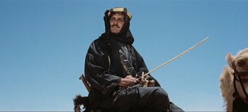 Movie still from “Lawrence of Arabia” (1962), directed by David Lean – A man sitting on top of a horse with a stick; Medium shot, Low angle