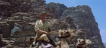 Movie still from “Lawrence of Arabia” (1962), directed by David Lean – A man riding a camel through a rocky area; Wide shot, Low angle