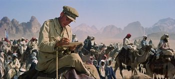 Movie still from “Lawrence of Arabia” (1962), directed by David Lean – A man sitting on top of a horse in front of a group of people; Medium shot, Low angle