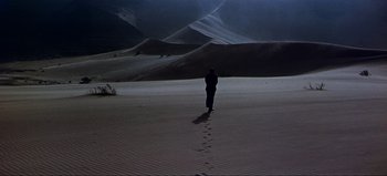 Movie still from “Lawrence of Arabia” (1962), directed by David Lean – A person walking in the desert at night time; Extreme Wide shot, High angle
