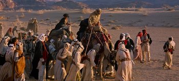 Movie still from “Lawrence of Arabia” (1962), directed by David Lean – A group of people riding on the back of a camel; Wide shot, High angle