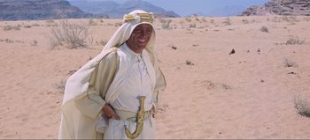 Movie still from “Lawrence of Arabia” (1962), directed by David Lean – A man dressed in a white robe and a white hat; Medium shot, Low angle