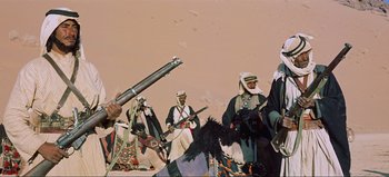 Movie still from “Lawrence of Arabia” (1962), directed by David Lean – A group of men standing next to each other holding guns; Medium shot, Low angle