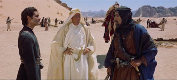 Movie still from “Lawrence of Arabia” (1962), directed by David Lean – A man in a white robe standing next to another man in a brown robe; Medium shot, Over the shoulder angle