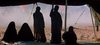 Movie still from “Lawrence of Arabia” (1962), directed by David Lean – Two women standing under an awning on the beach; Wide shot, Over the shoulder angle