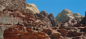 Movie still from “Lawrence of Arabia” (1962), directed by David Lean – A group of people sitting on top of a rock formation; Extreme Wide shot, High angle
