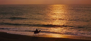 Movie still from “Lawrence of Arabia” (1962), directed by David Lean – A person riding a horse on a beach at sunset; Extreme Wide shot, High angle