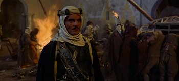 Movie still from “Lawrence of Arabia” (1962), directed by David Lean – A man dressed as a middle eastern man in front of a group of people; Medium shot, Over the shoulder angle