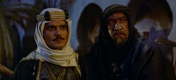 Movie still from “Lawrence of Arabia” (1962), directed by David Lean – Two men dressed in medieval clothing , one of which has a beard; Medium shot, Over the shoulder angle
