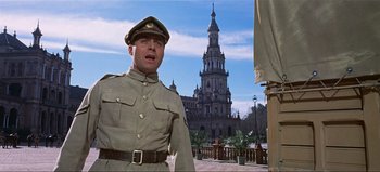 Movie still from “Lawrence of Arabia” (1962), directed by David Lean – A man in a military uniform standing in front of a building; Medium shot, Low angle