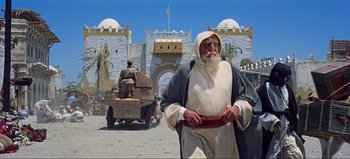 Movie still from “Lawrence of Arabia” (1962), directed by David Lean – An old man dressed as jesus stands in front of an armored vehicle; Wide shot, Low angle