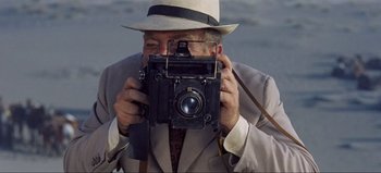Movie still from “Lawrence of Arabia” (1962), directed by David Lean – An older man taking a picture with an old camera; Close Up shot, High angle