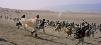 Movie still from “Lawrence of Arabia” (1962), directed by David Lean – A group of people running across the sand dunes; Extreme Wide shot, High angle