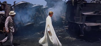 Movie still from “Lawrence of Arabia” (1962), directed by David Lean – A man in a white robe walking in front of a fire; Wide shot, Low angle